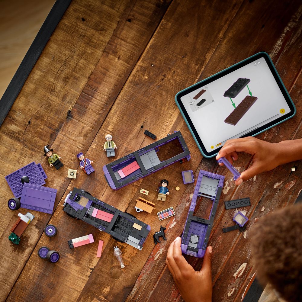 LEGO 76446 Eine Person baut mit LEGO-Steinen und einem Tablet auf einem Holztisch.