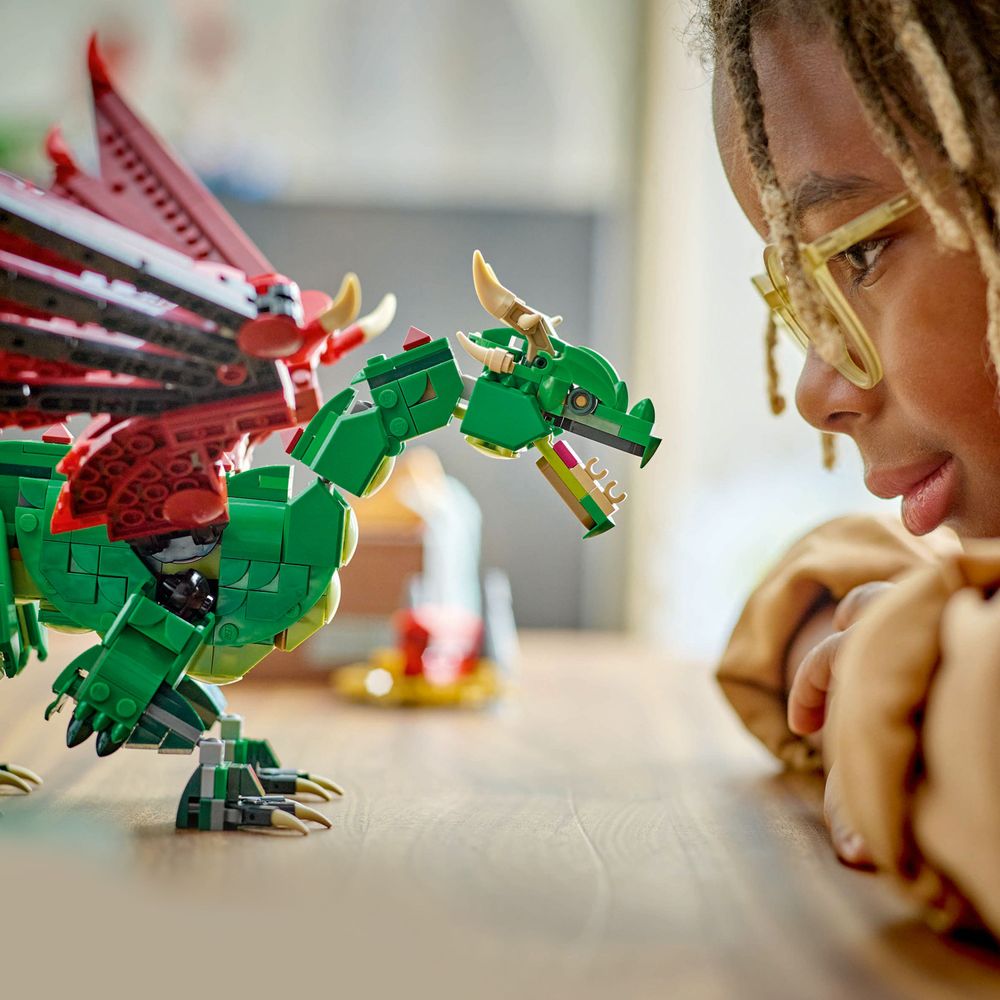 LEGO 31161 Ein Kind betrachtet fasziniert einen grünen LEGO-Drachen mit roten Flügeln.