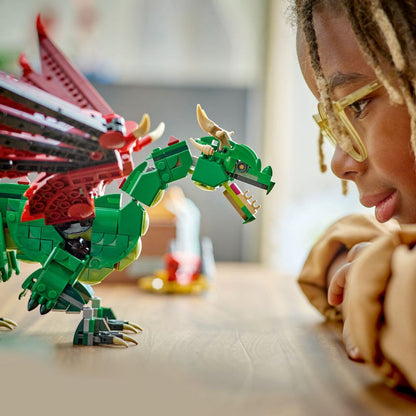 LEGO 31161 Ein Kind betrachtet fasziniert einen grünen LEGO-Drachen mit roten Flügeln.