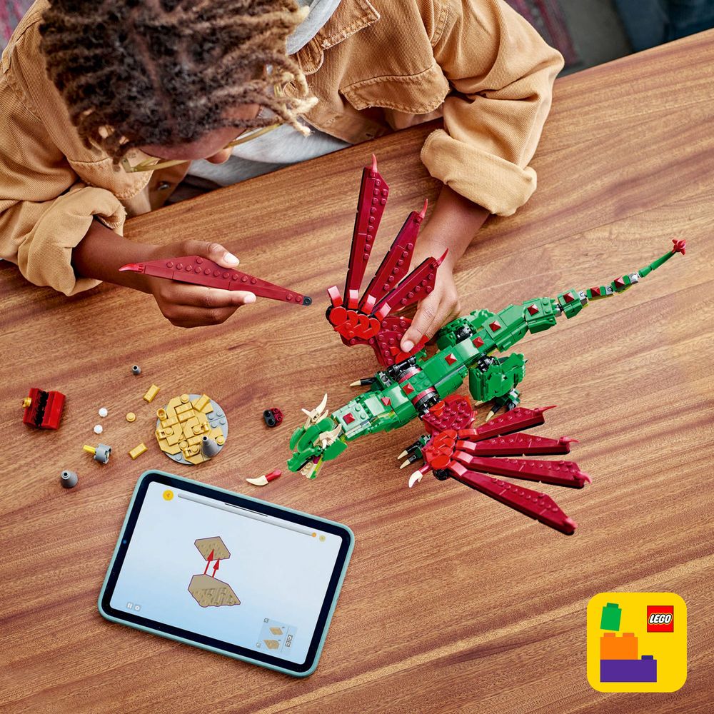 LEGO 31161 Ein Kind baut mit LEGO-Steinen einen beeindruckenden grünen Drachen am Tisch.
