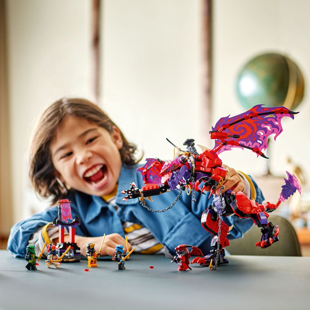 LEGO 71832 Ein fröhliches Kind spielt mit dem Chaosdrache und LEGO-Figuren auf einem Tisch.