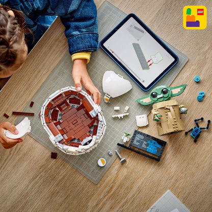 LEGO 75403 Ein Kind baut mit LEGO Steinen eine Repulsorwiege für Grogu mit Anleitung auf dem Tablet.