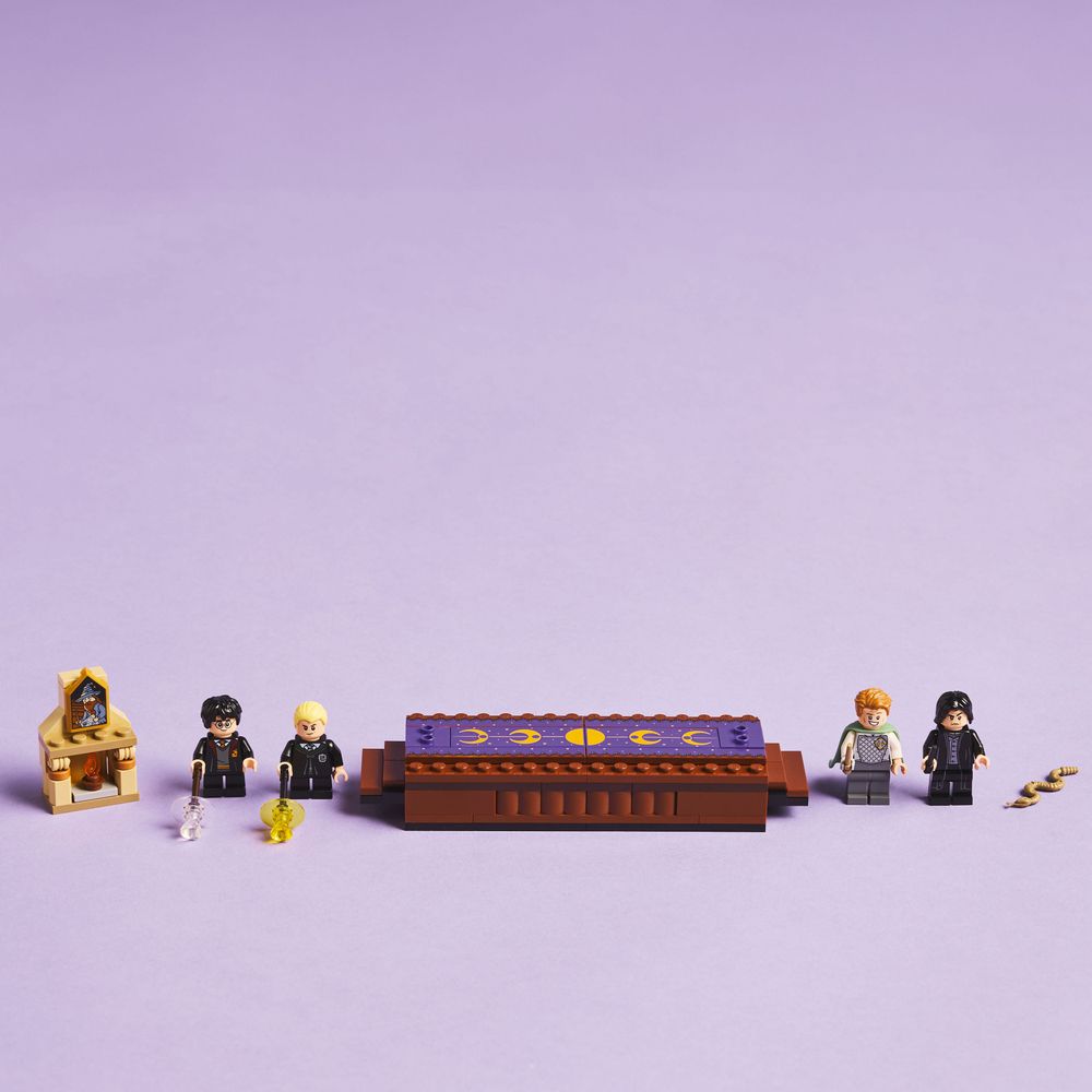 LEGO 76441 Auf einem lila Hintergrund sind LEGO-Minifiguren und ein Zaubertisch abgebildet.