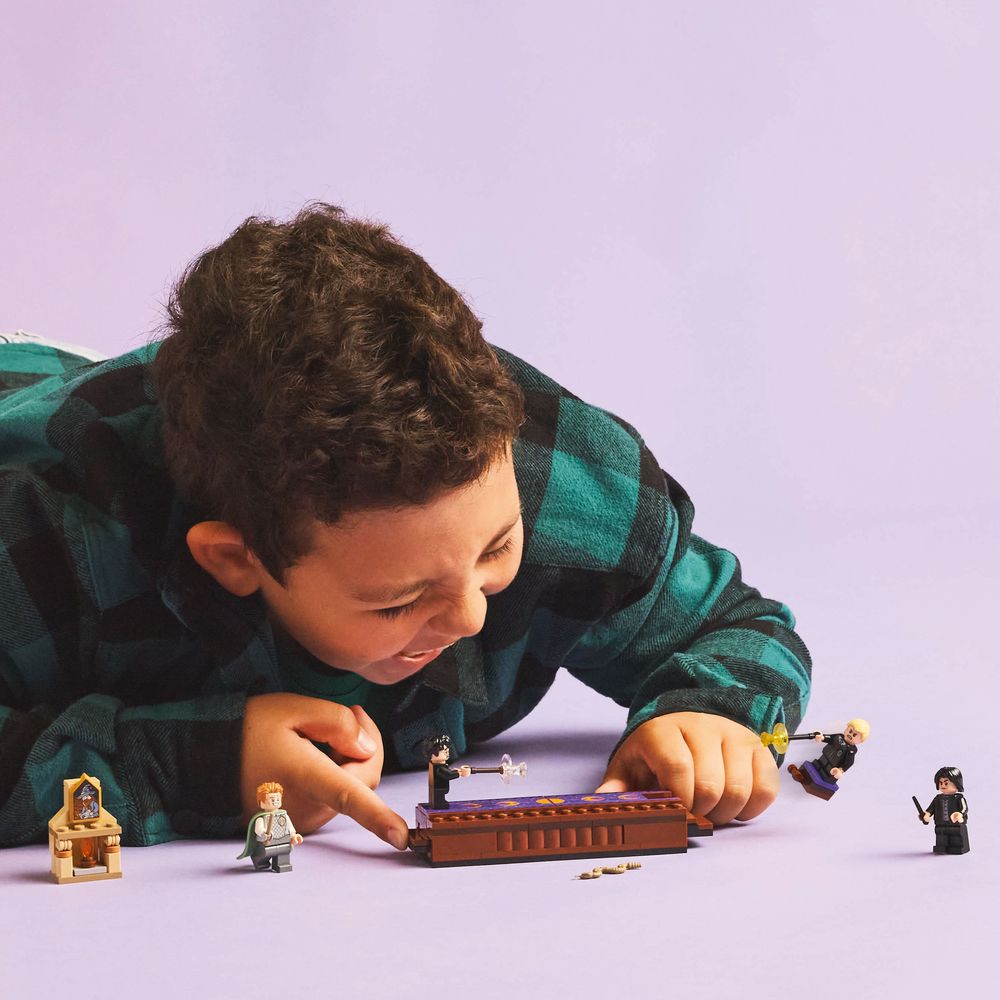 LEGO 76441 Ein Junge spielt mit einem LEGO Hogwarts-Set umgeben von Figuren und Zubehör.